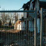 a building with a bunch of rubble behind a fence