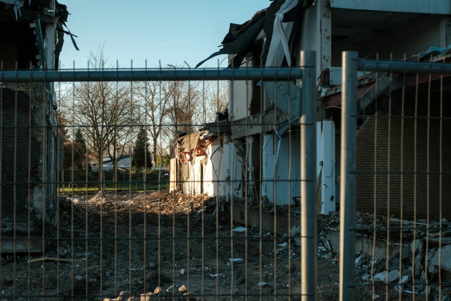 a building with a bunch of rubble behind a fence